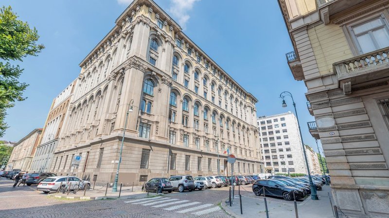 Palazzo in pietra con finestre ad arco e auto in sosta all’angolo, Via Confienza 10 a Torino