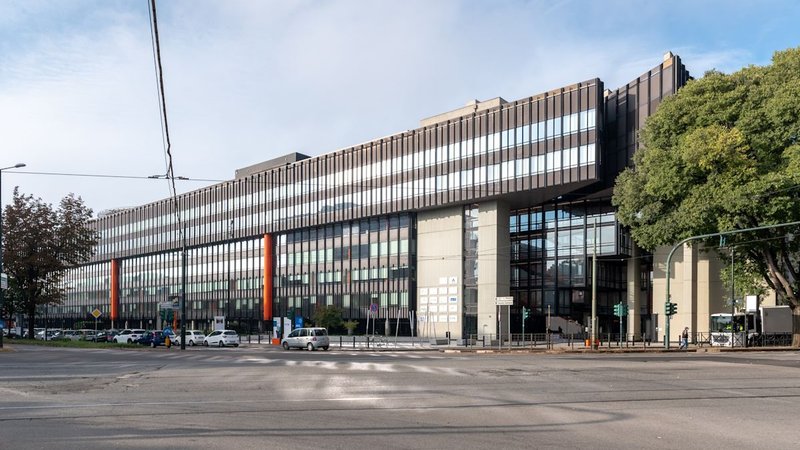 Edificio basso e allungato con fascia vetrata e pilastri arancioni visto dall’incrocio, Corso Francesco Ferrucci 112 a Torino