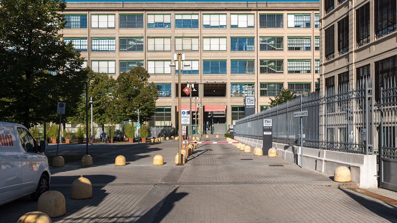 Viale d’ingresso con dissuasori verso un lungo edificio a nastri di vetrate, Via Nizza 262 a Torino